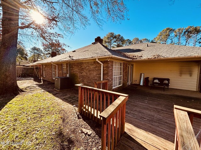 back of property featuring a deck, a chimney, central AC, and brick siding