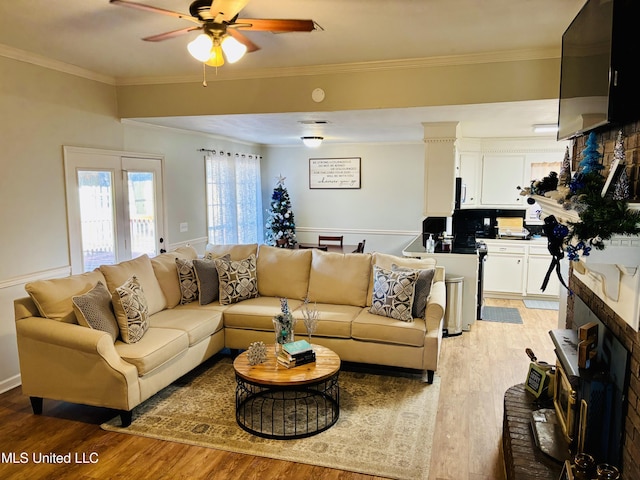 living room featuring crown molding, light hardwood / wood-style flooring, and ceiling fan