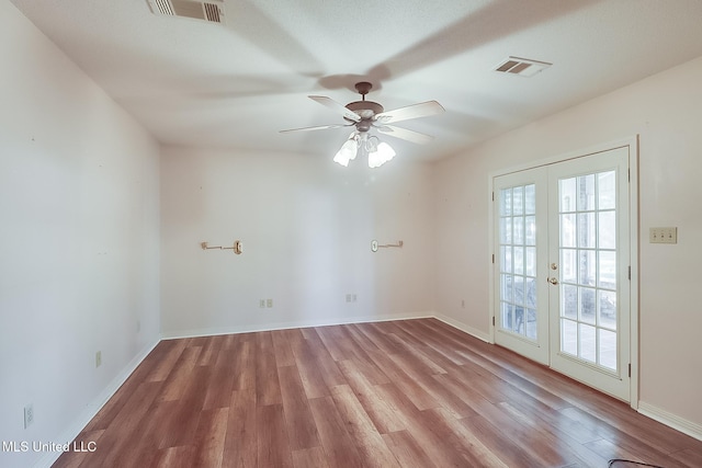 empty room featuring french doors, ceiling fan, and light wood-type flooring