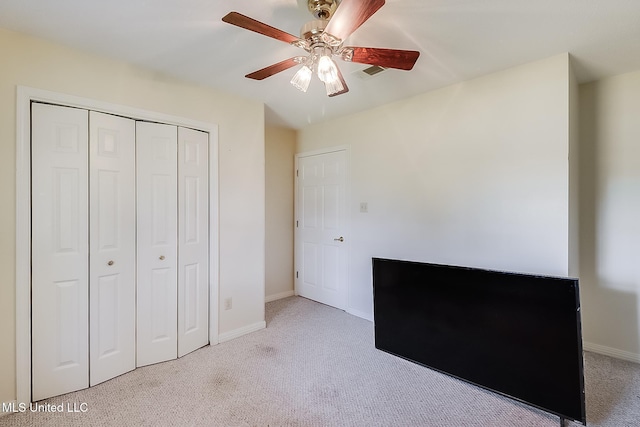 unfurnished bedroom with ceiling fan, a closet, and light carpet