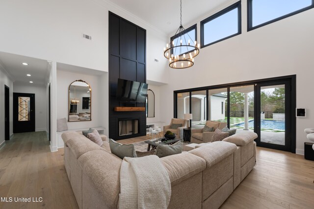 living area featuring light wood finished floors, a fireplace, visible vents, and a chandelier