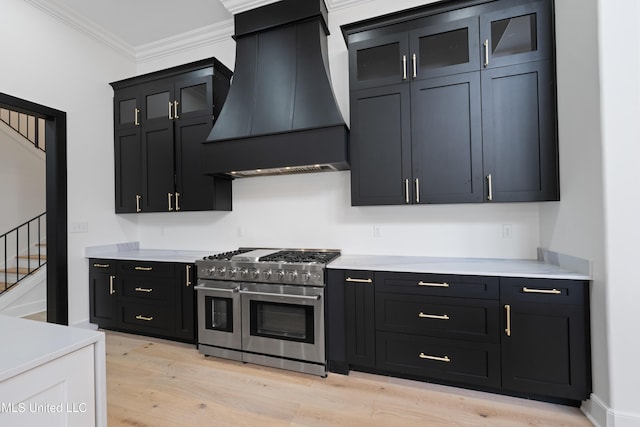 kitchen with dark cabinets, light countertops, ornamental molding, custom exhaust hood, and double oven range