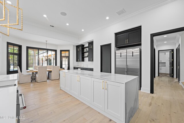 kitchen with high quality fridge, light wood-style flooring, a notable chandelier, a kitchen island, and open shelves