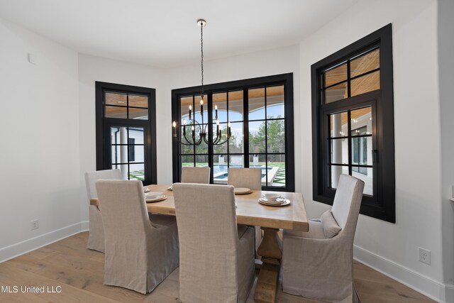 dining space featuring light wood finished floors, baseboards, and a notable chandelier