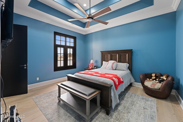 bedroom featuring crown molding, wood finished floors, a raised ceiling, and baseboards