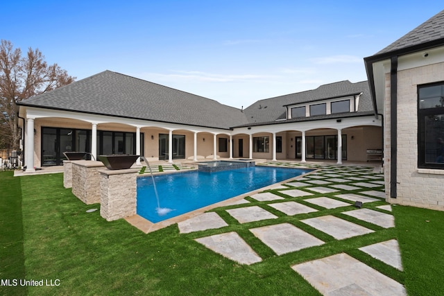 view of swimming pool featuring a yard, a pool with connected hot tub, and a patio