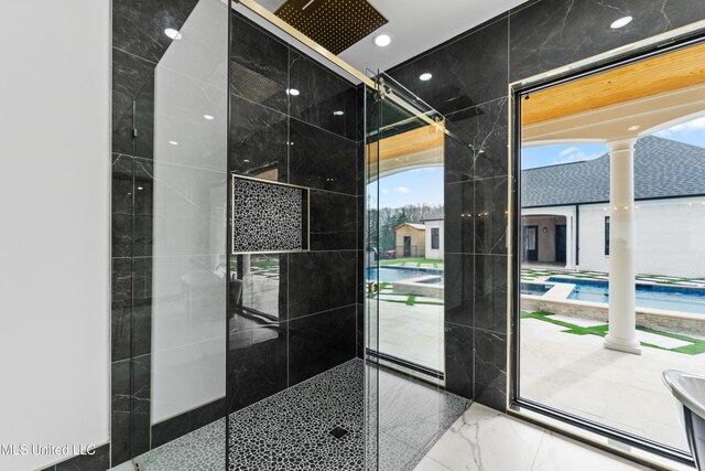 bathroom featuring marble finish floor and walk in shower