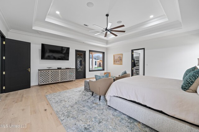 bedroom with visible vents, a raised ceiling, light wood-style flooring, and crown molding