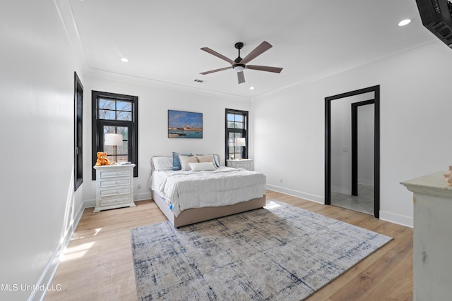 bedroom featuring light wood finished floors, multiple windows, baseboards, and crown molding