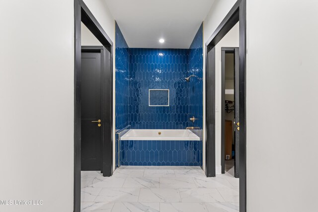 full bathroom featuring tiled tub and marble finish floor