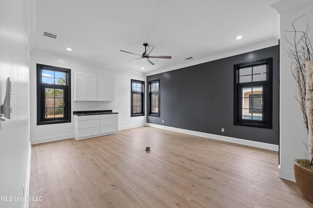 unfurnished living room featuring ornamental molding, visible vents, plenty of natural light, and light wood finished floors