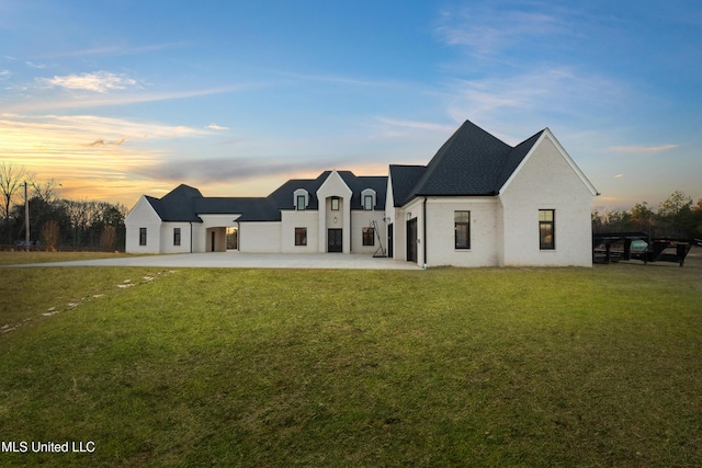 back of property at dusk with a lawn