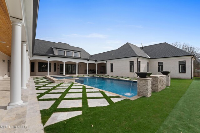 view of swimming pool with a patio, a yard, and a pool with connected hot tub