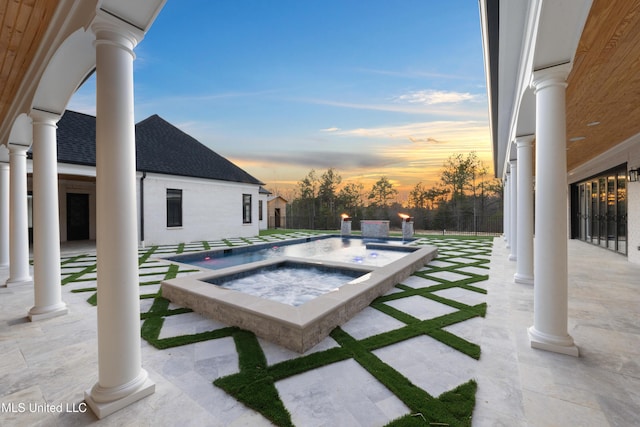 pool at dusk featuring an in ground hot tub, fence, an outdoor pool, and a patio