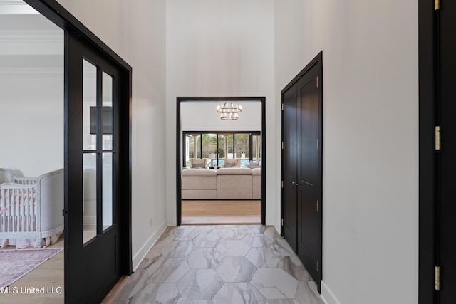 hall with baseboards, a towering ceiling, and a notable chandelier