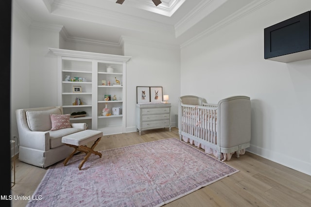 bedroom featuring a tray ceiling, wood finished floors, and ornamental molding