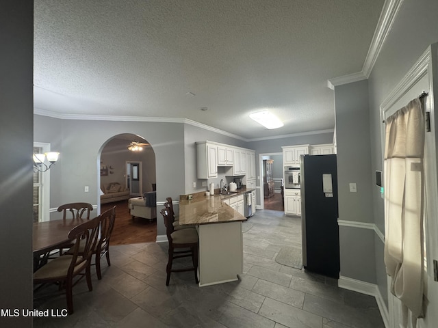 2610 Dickens Place Dr, Southaven, MS 38671 - kitchen with stainless steel appliances, a textured ceiling, arched walkways, white cabinetry, and a kitchen breakfast bar