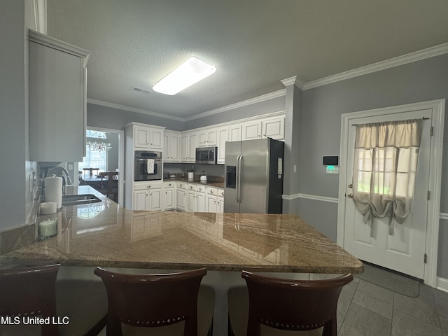 2610 Dickens Place Dr, Southaven, MS 38671 - kitchen featuring appliances with stainless steel finishes, a peninsula, crown molding, a breakfast bar area, and dark stone counters