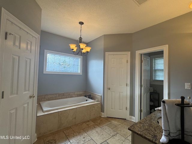 2610 Dickens Place Dr, Southaven, MS 38671 - bathroom featuring a bath, a chandelier, vanity, stone tile flooring, and a textured ceiling