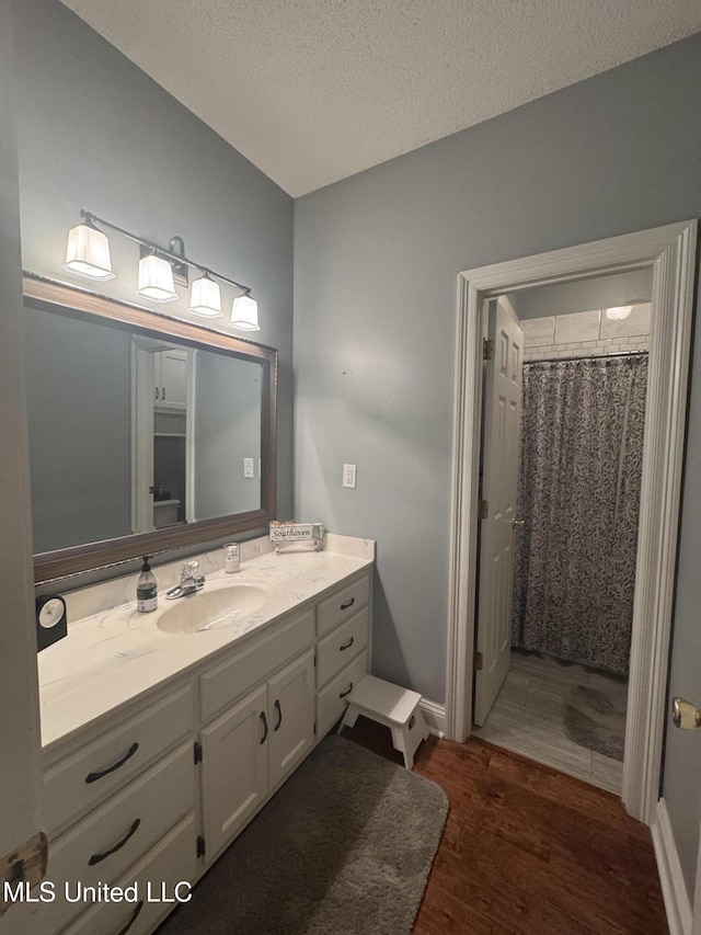 2610 Dickens Place Dr, Southaven, MS 38671 - bathroom featuring vanity, wood finished floors, a textured ceiling, and a shower with shower curtain