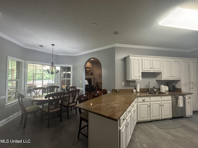 2610 Dickens Place Dr, Southaven, MS 38671 - kitchen with stainless steel dishwasher, a textured ceiling, arched walkways, a chandelier, and white cabinets