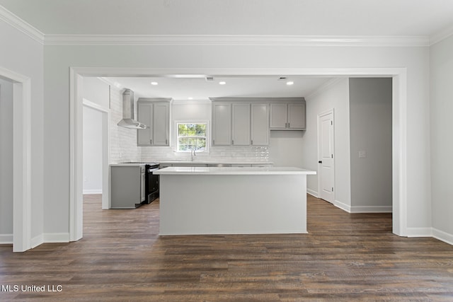 kitchen with wall chimney range hood, stainless steel stove, dark hardwood / wood-style floors, gray cabinetry, and a center island