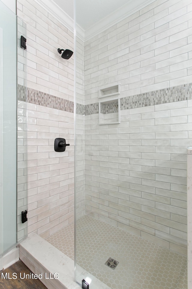 bathroom with ornamental molding and a shower with shower door