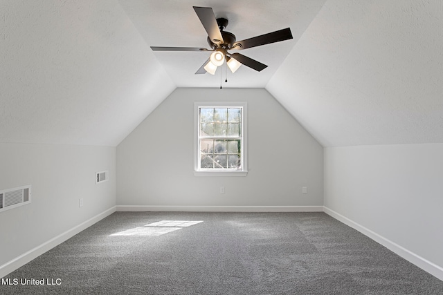 bonus room with lofted ceiling, a textured ceiling, carpet flooring, and ceiling fan