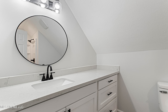 bathroom featuring vanity, vaulted ceiling, and toilet