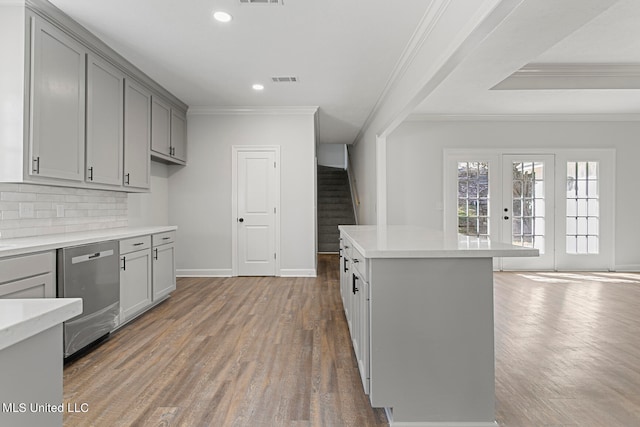 kitchen with stainless steel dishwasher, hardwood / wood-style floors, decorative backsplash, and gray cabinets