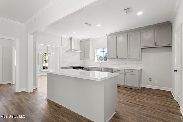 kitchen featuring a healthy amount of sunlight, wall chimney exhaust hood, a center island, and dark hardwood / wood-style floors