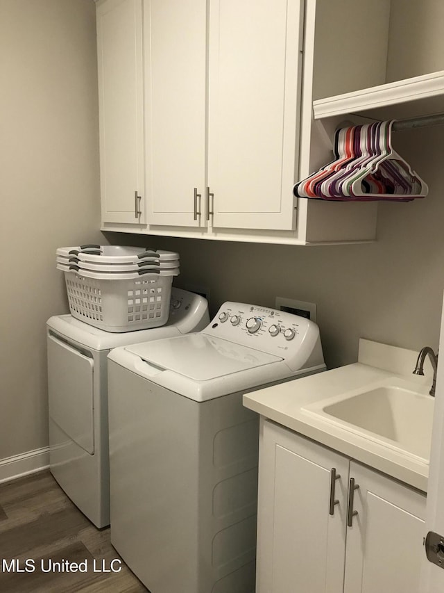 laundry room featuring cabinets, sink, washer and dryer, and dark hardwood / wood-style floors