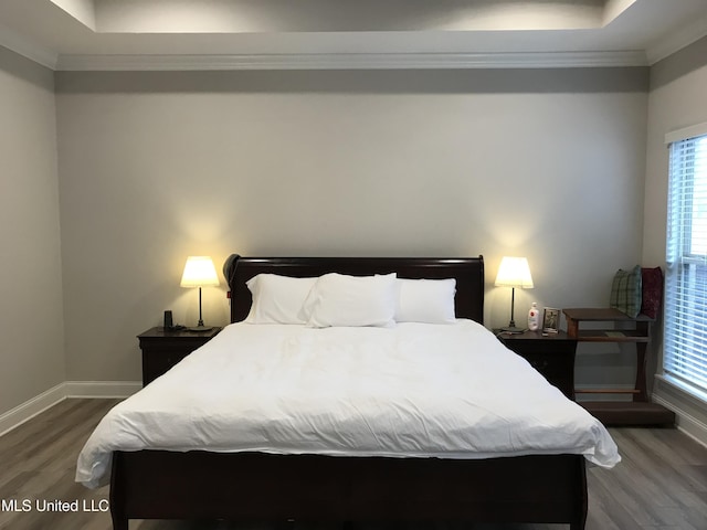 bedroom featuring dark hardwood / wood-style floors, a raised ceiling, and crown molding