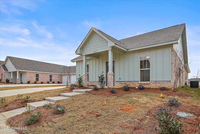 view of front of house with a front yard, central AC unit, and a garage