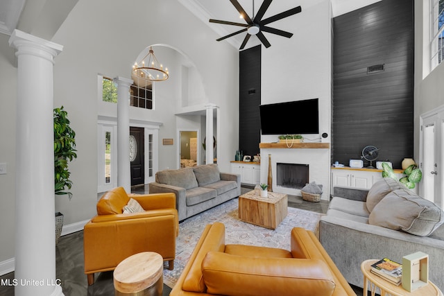 living room with a towering ceiling, ornate columns, hardwood / wood-style floors, and plenty of natural light