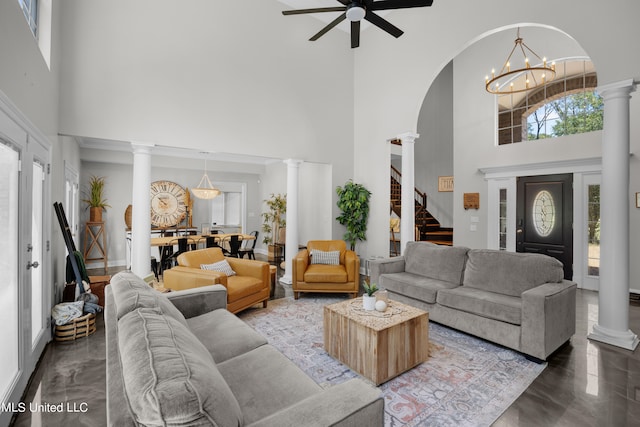 living room with ceiling fan with notable chandelier, a high ceiling, and decorative columns