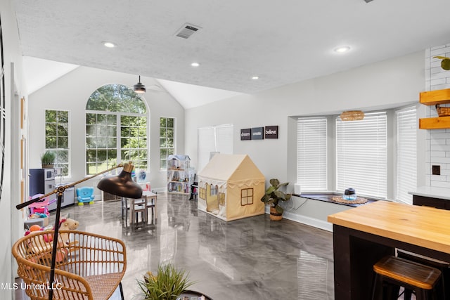 interior space with a textured ceiling, ceiling fan, and vaulted ceiling