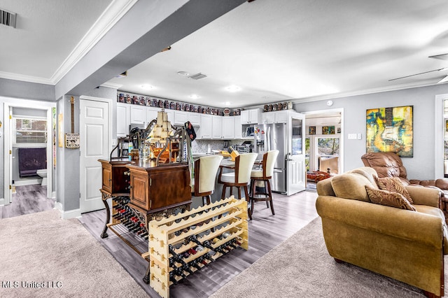 living room featuring ceiling fan, light hardwood / wood-style floors, and crown molding