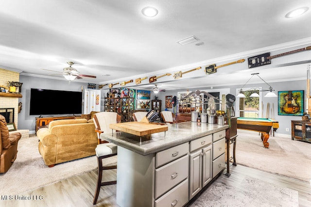 interior space featuring gray cabinetry, crown molding, light hardwood / wood-style flooring, a breakfast bar area, and pool table