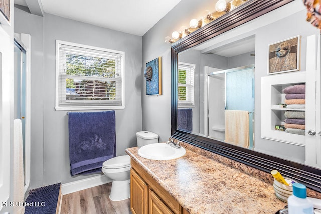 bathroom with toilet, a wealth of natural light, a shower with door, and hardwood / wood-style flooring