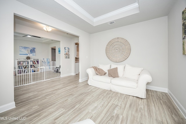 living room with baseboards, visible vents, wood finished floors, and a tray ceiling