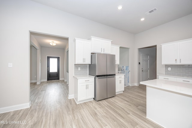 kitchen featuring white cabinetry, light countertops, light wood-style flooring, and freestanding refrigerator