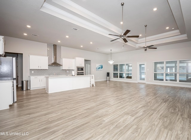 unfurnished living room featuring recessed lighting, ornamental molding, ceiling fan, and a raised ceiling