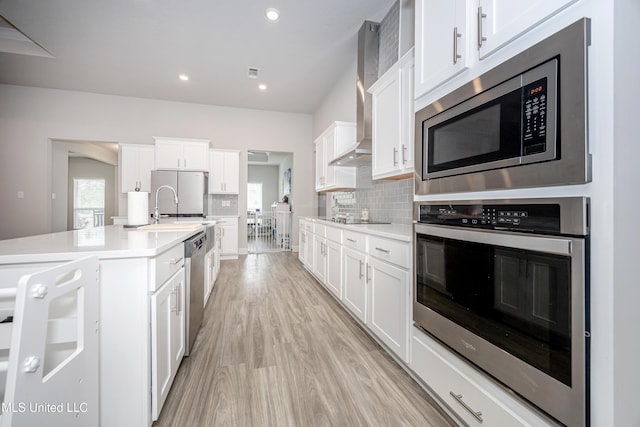 kitchen with appliances with stainless steel finishes, light wood-style flooring, light countertops, and white cabinets