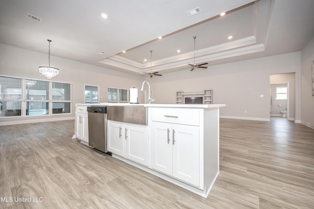 kitchen with a tray ceiling, visible vents, baseboards, stainless steel dishwasher, and open floor plan