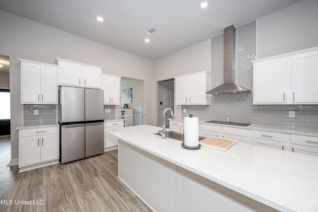 kitchen featuring decorative backsplash, wall chimney exhaust hood, visible vents, white cabinetry, and freestanding refrigerator