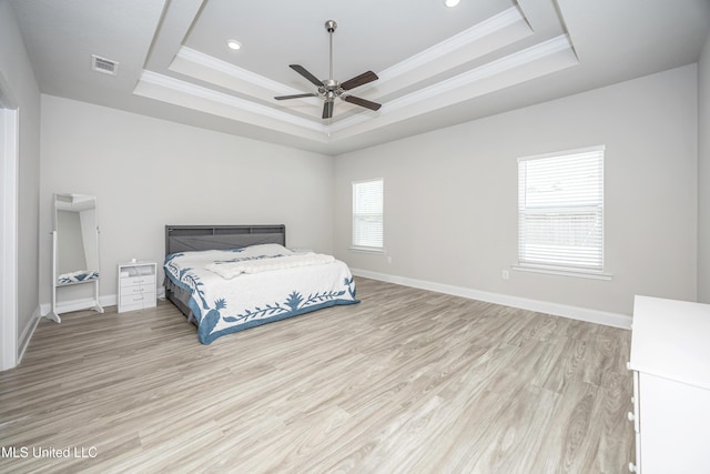 bedroom with visible vents, a raised ceiling, light wood-type flooring, and ornamental molding