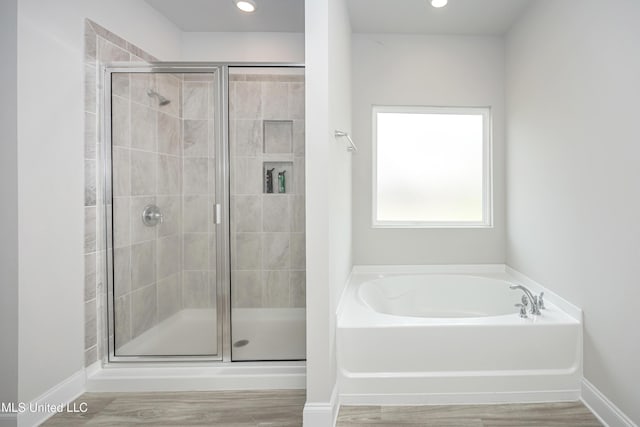 full bath featuring wood finished floors, recessed lighting, a bath, and a stall shower