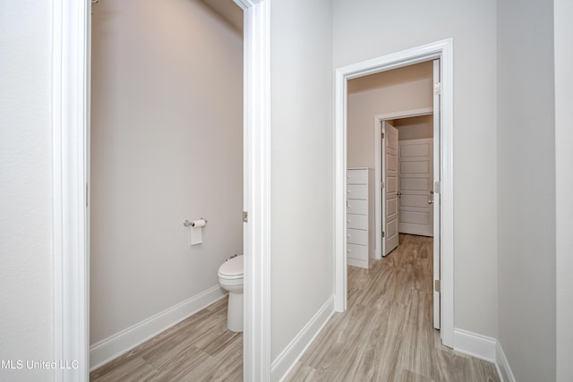 corridor with light wood-type flooring and baseboards