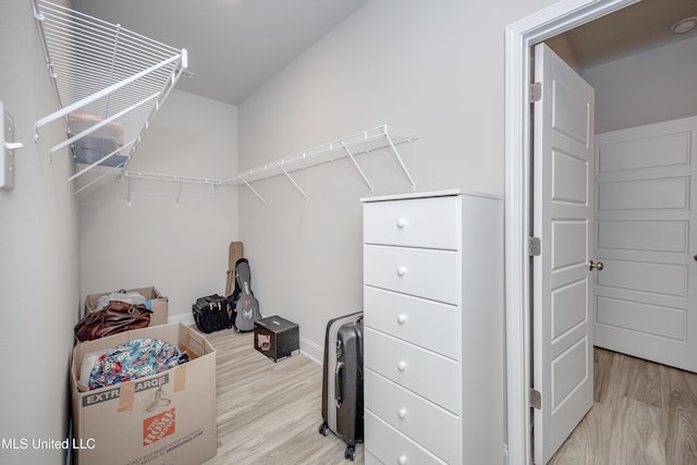 walk in closet with light wood finished floors